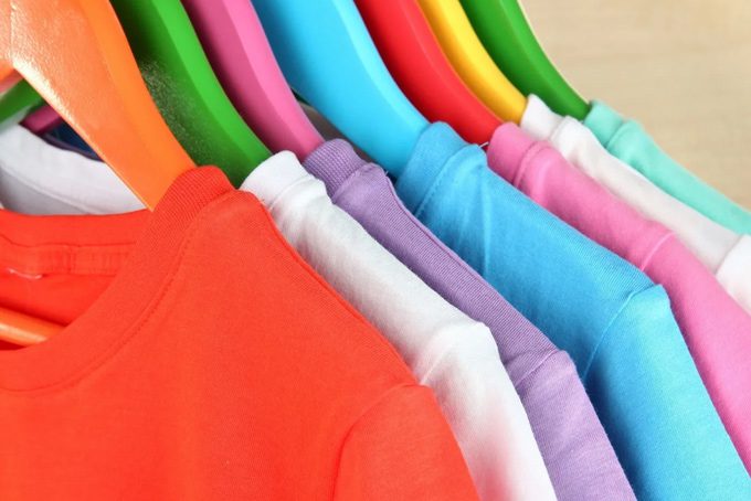 A bunch of different colored shirts hanging up